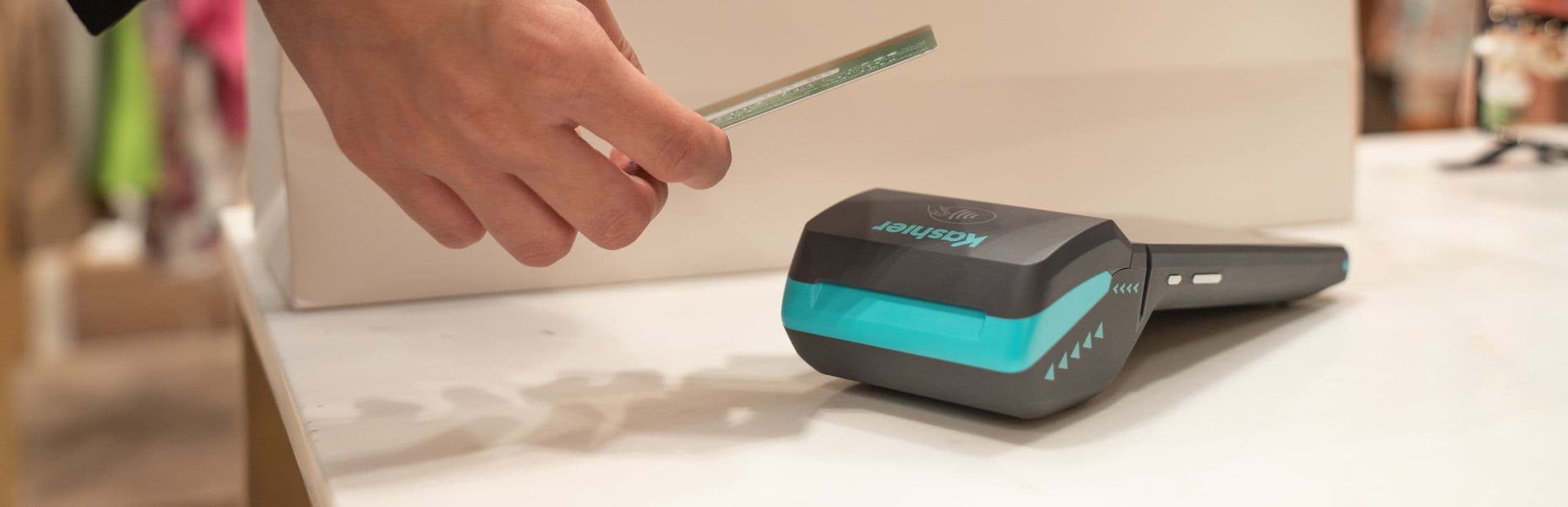 A customer taps a bank card on a Kashier POS terminal at a store counter